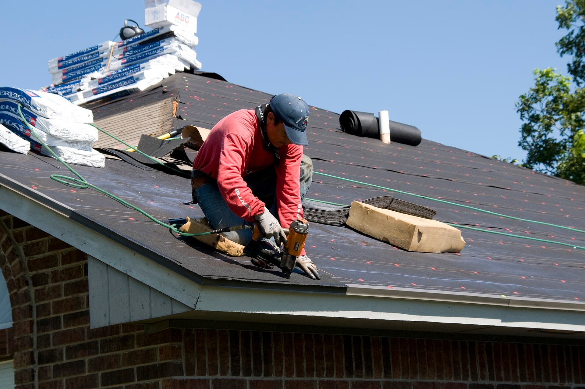 A roofer nailing down architectural shingles