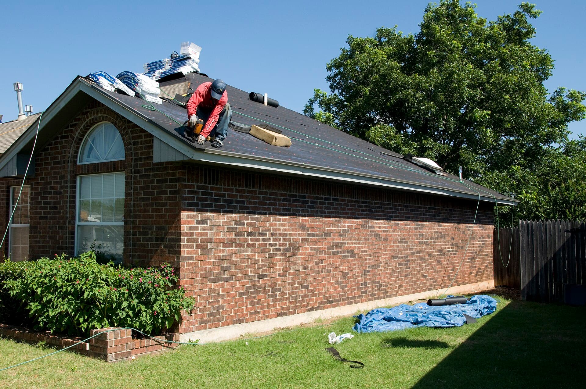 A roofer re-roofing a brick ranch house